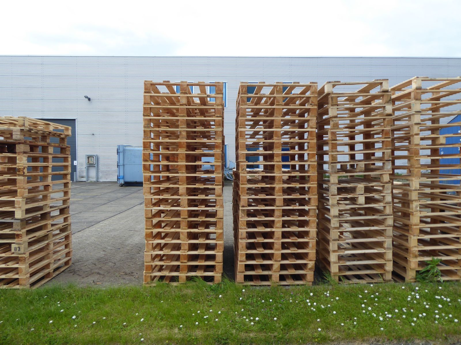 Stacks of wooden pallets beside an industrial warehouse