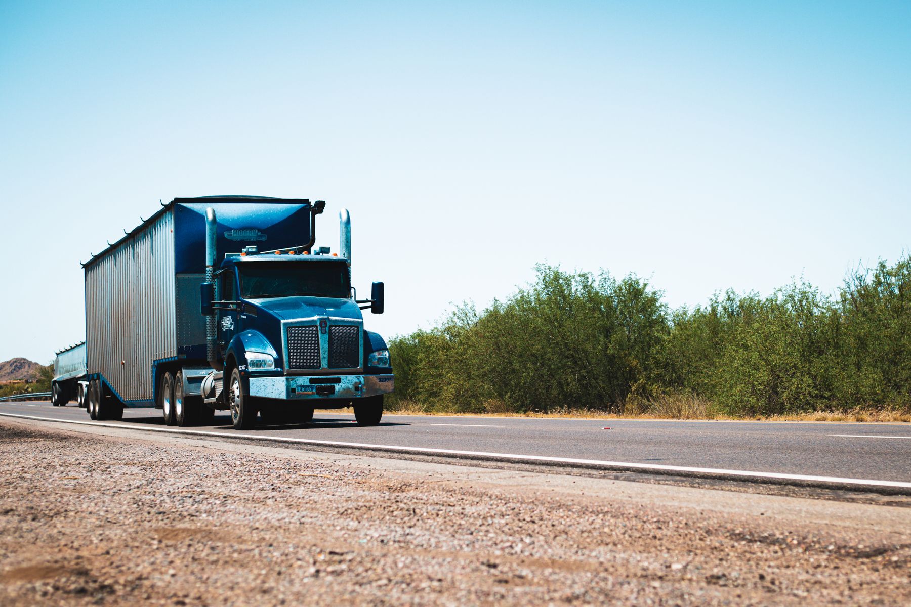 Blue semi-truck traveling on an open rural highway