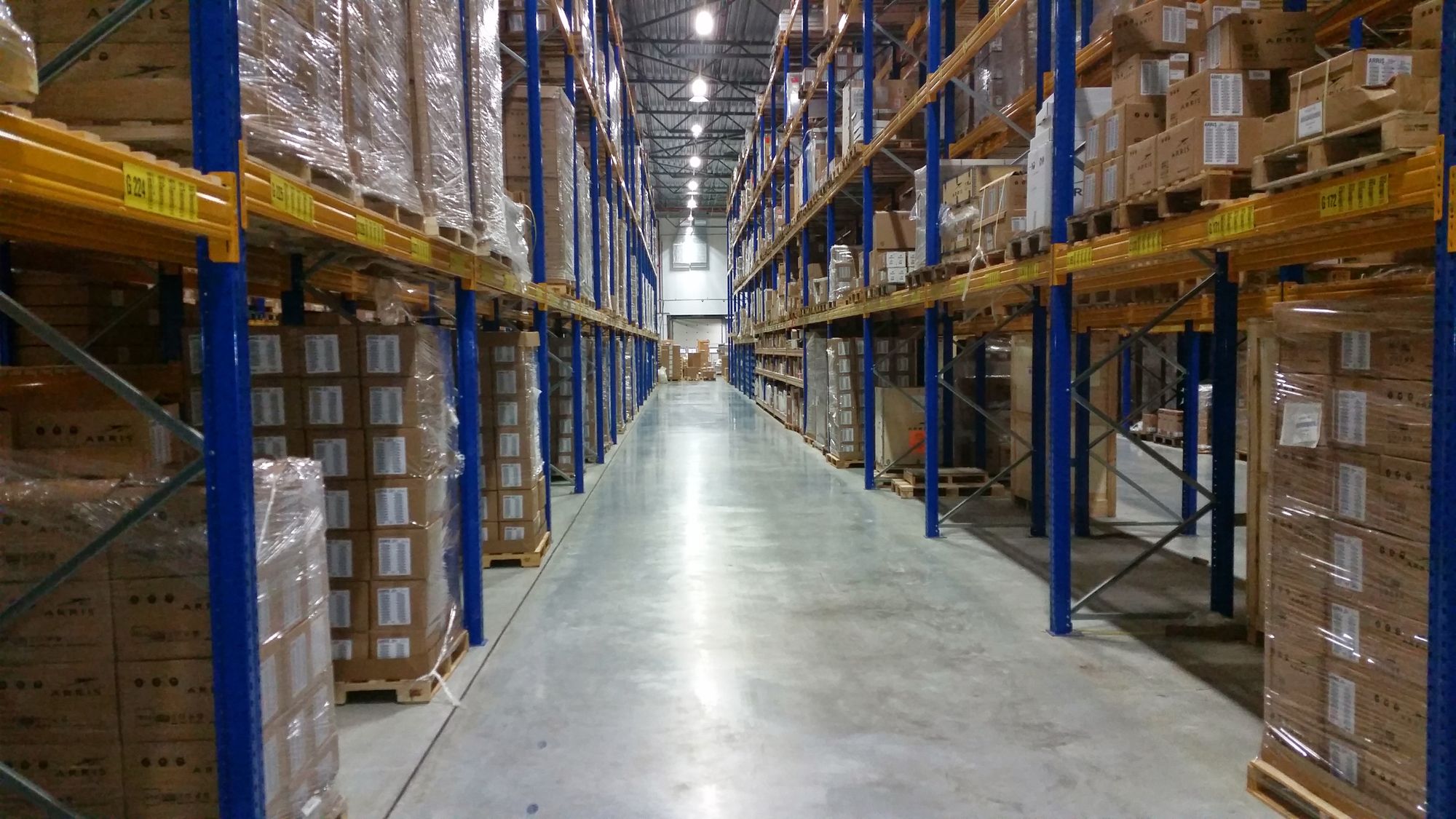 Long warehouse aisle lined with stacked cartons on pallet racks